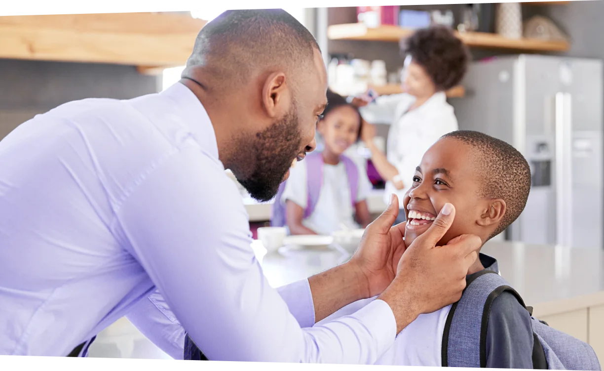Família afro-descendente na cozinha preparando filhos para escola.