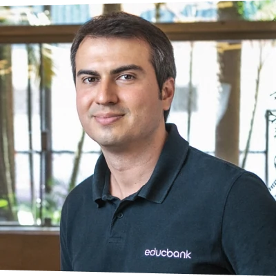 Foto de Danilo Costa. Homem branco de cabelos e olhos castanhos, camisa polo azul marinho com logo do Educbank.