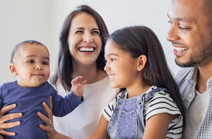 Família sorrindo tranquila sentada no sofá.