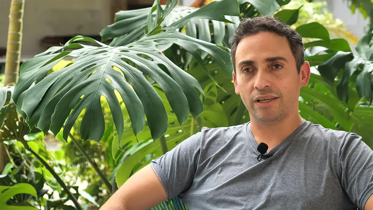 Luiz Carlos, homem branco, cabelos e olhos pretos, veste camiseta cinza no quintal escolar.